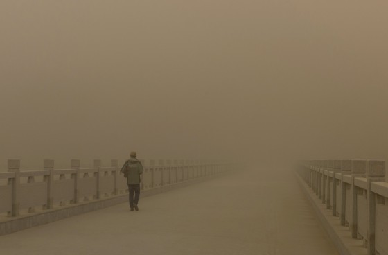 A staff of Mogao Grottoes walks on a bridge engulfed by sand as a dust storm strikes Dunhuang