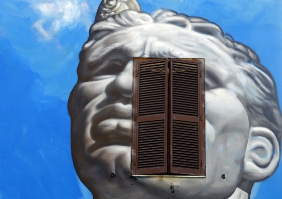 An half closed window is seen on a house painted with graffiti in a Rome neighbourhood