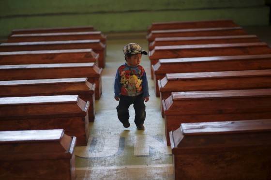 A boy walks between empty coffins before anthropologists place the remains of victims of the internal armed conflict in them, in Nebaj