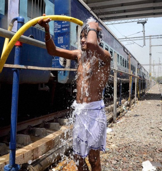 Allahabad: A man takes bath under a train water supplying pipe at a railway station in Allahabad on Saturday. Most of north India has been reeling under heat wave conditions with temperature soaring to over 46 degree Celsius. PTI Photo  (PTI5_23_2015_000094B)